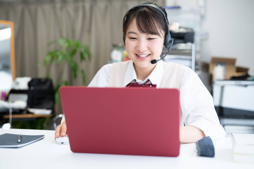 ヘッドセットを着けてノートPCで学習する高校生