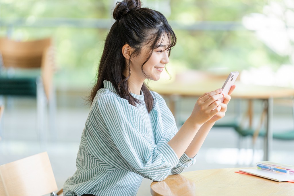 カフェでスマホを見てスキマ学習をする女性