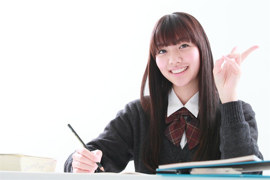 ノートを前に笑顔でポーズする制服の生徒