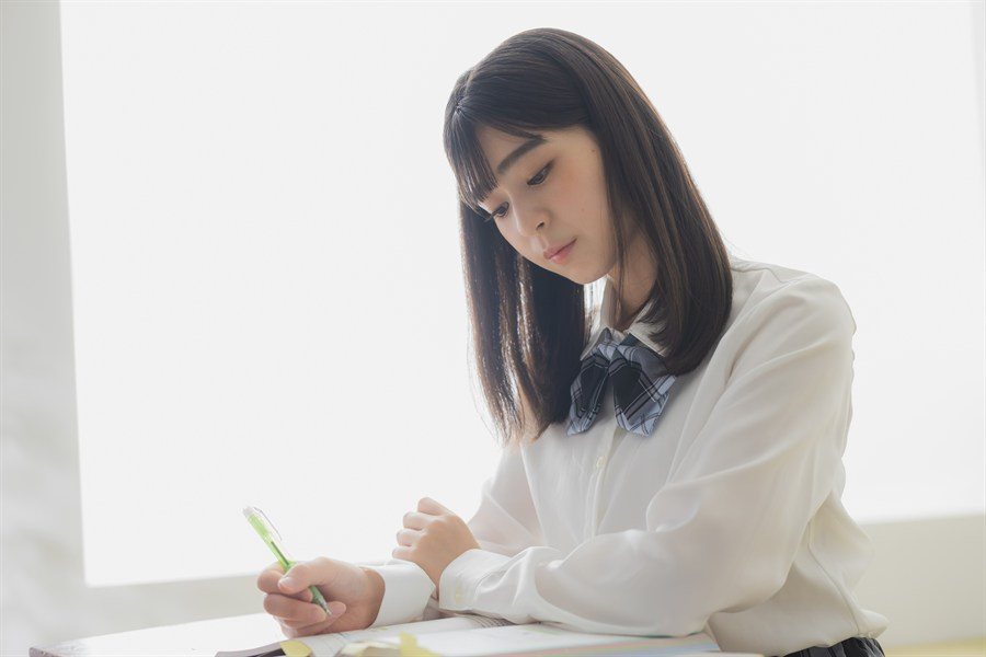 ノートにペンで書き進める制服の生徒