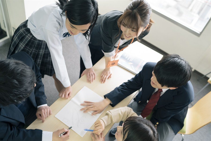 先生と生徒が机を囲んで学ぶ様子