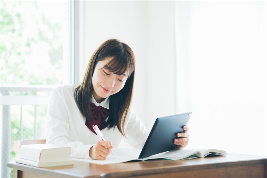 タブレットを立ててノートに書く制服の生徒