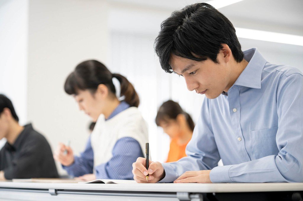 教室でノートに書き込む社会人