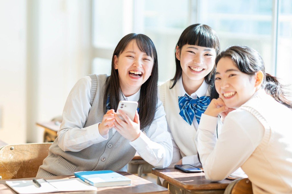 スマホを見て笑う学生たち