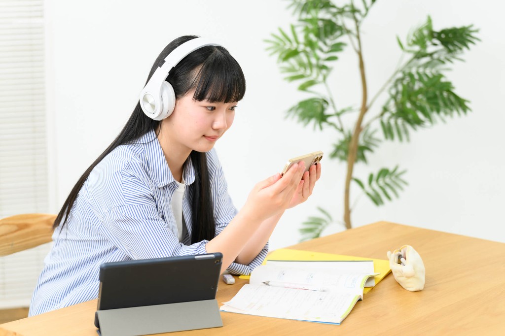 ヘッドホンでスマホとタブレットを使い学習する生徒
