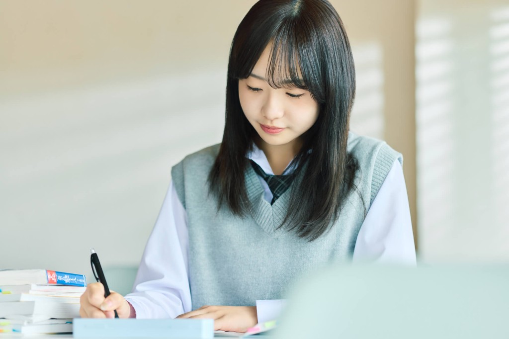 ノートに書き込みながら学習を続ける高校生