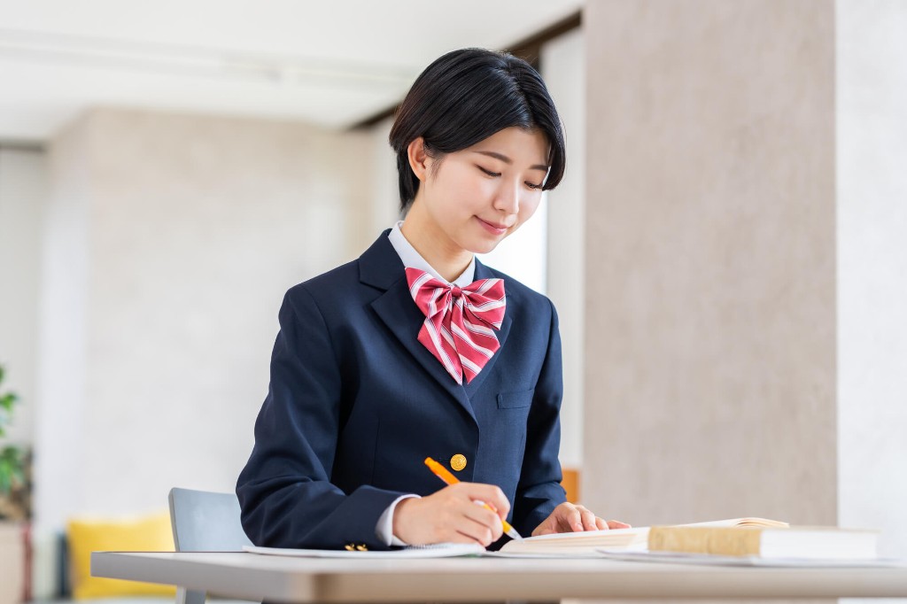 制服でノートに書きながら準2級の学習をする高校生