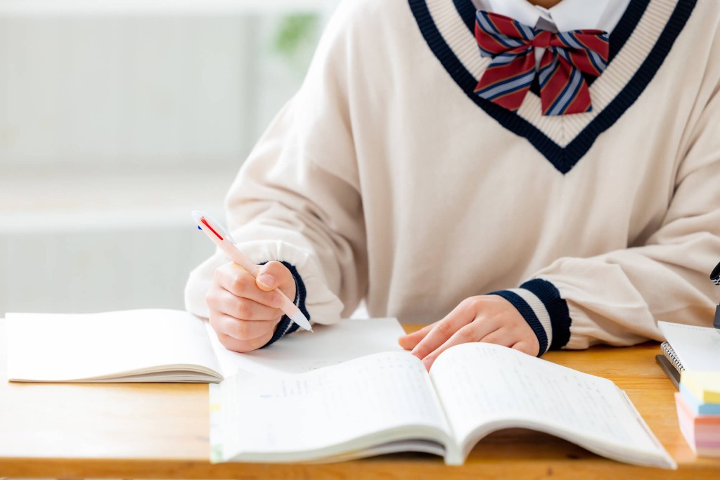 ノートにペンで書き進める高校生