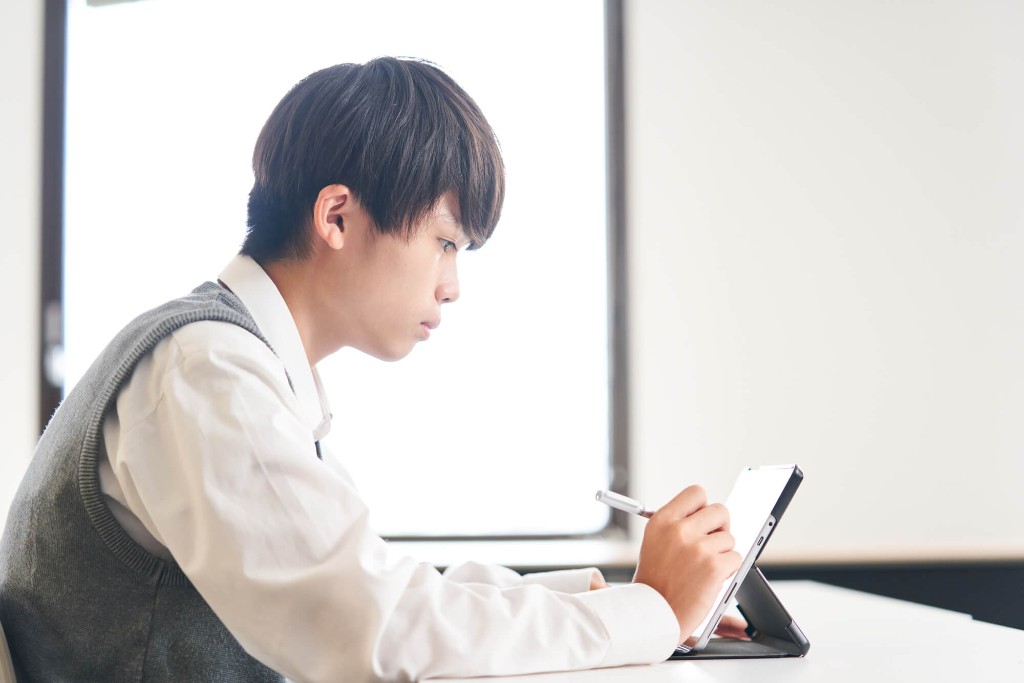 タブレットに書きながら学習する高校生