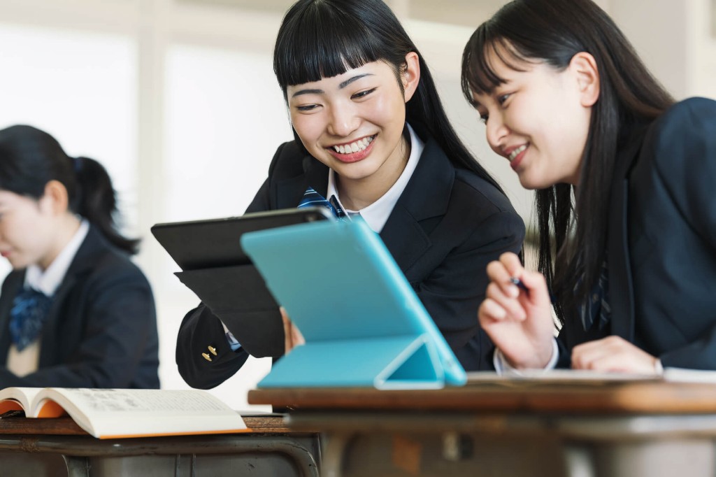教室でタブレットを見ながら学ぶ高校生