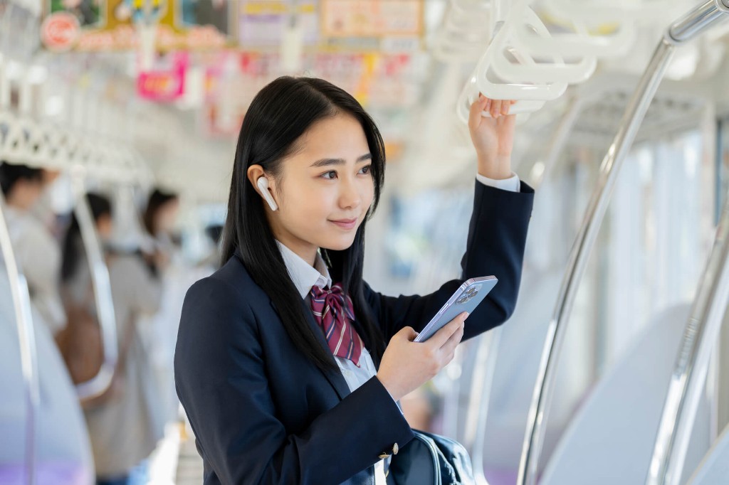 電車の中でスマホを使う女子学生