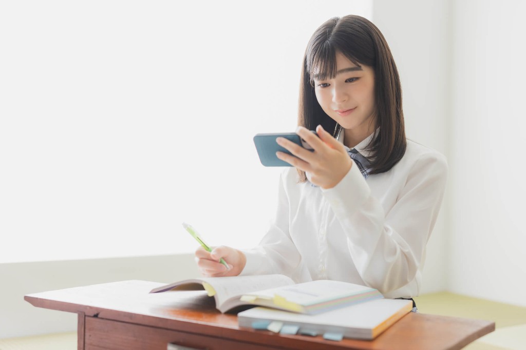 スマホと参考書で復習する女子学生