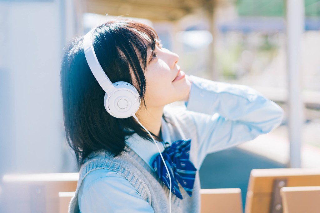 ヘッドフォンをつけて待ち時間に学習する女子学生